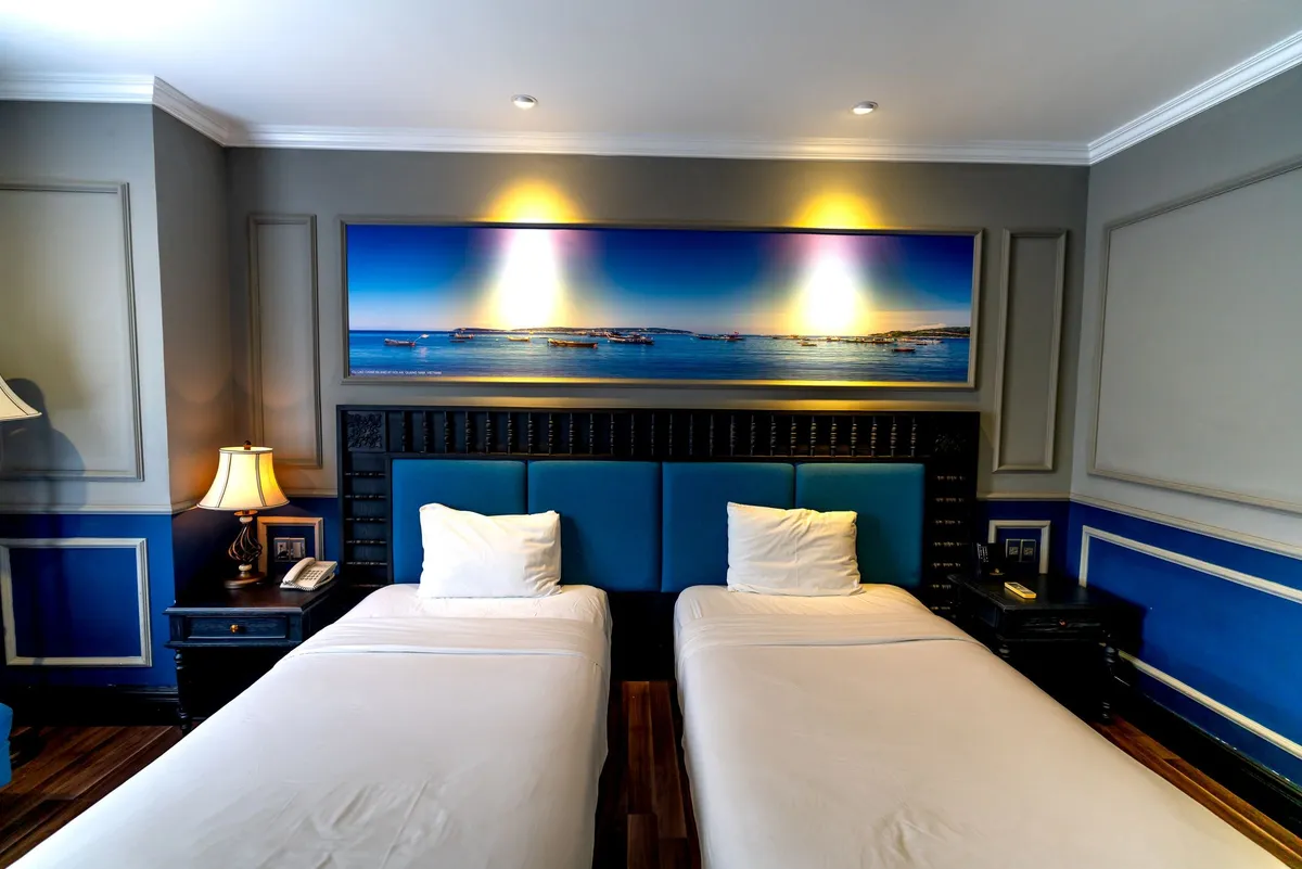 A two-bed air-conditioned room with bedside lamps and crisp white linen